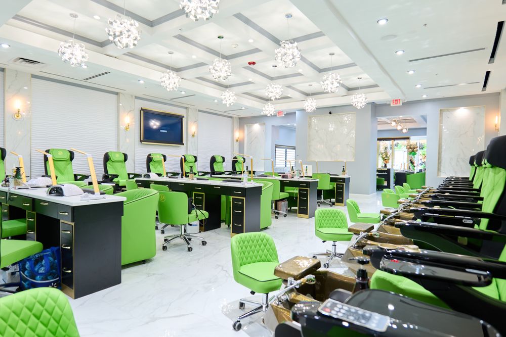 Elegant nail salon with burgundy chairs, manicure stations, and chandelier ceiling